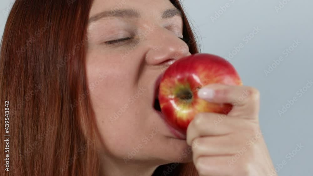 Young caucasian woman eating ripe red apple with closed eyes, enjoying fresh organic snack, healthy eating and lifestyle concept Young caucasian woman eating ripe red apple with closed eyes, enjoying fresh organic snack, healthy eating and lifestyle concept