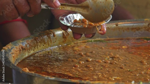 Hands serving gravy in a take away plate in india street food market