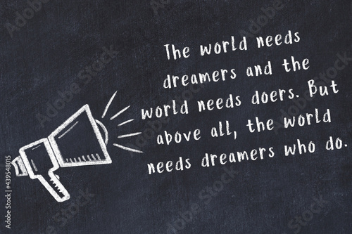 Chalk sketch of loudspeaker on black desk and movitational quote