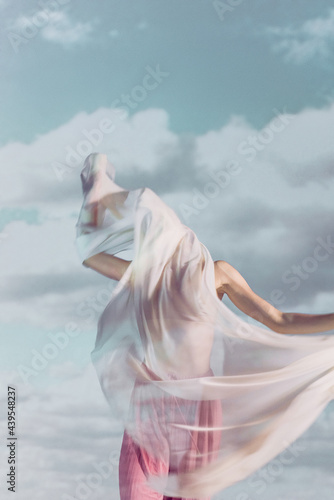 Person wrapped in fabric with clouds behind her photo