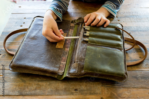Boy pulls pencil from leather portfolio