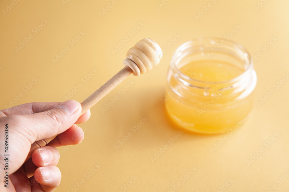 Male hand dipper and honey jar on yellow background. Male hand dipper and honey jar on yellow background.