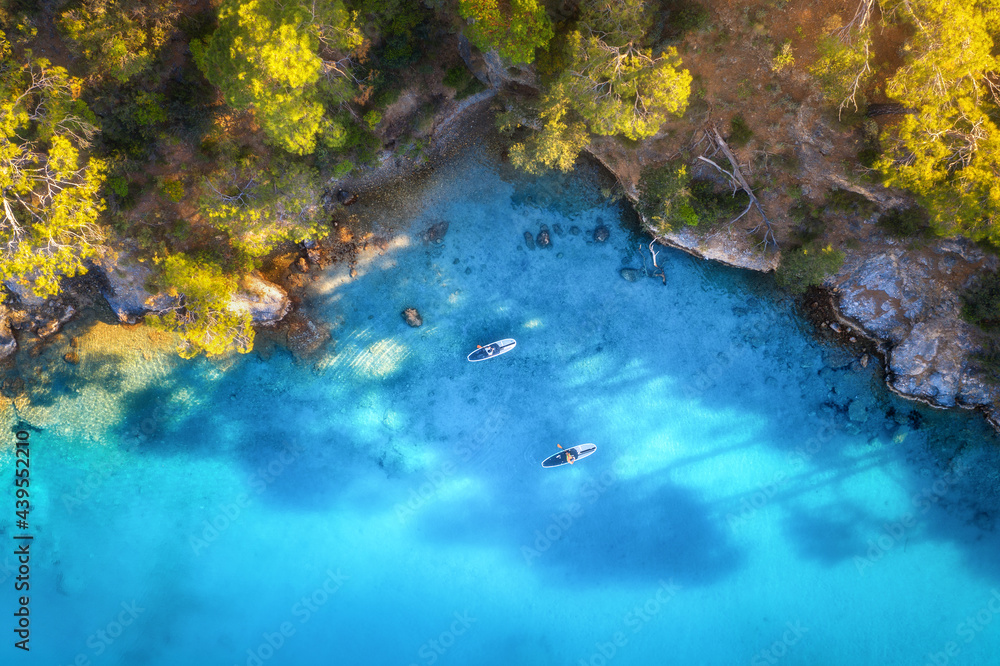 Aerial view of people on floating sup boards on blue sea, rocks, trees at sunset in summer. Blue lagoon, Oludeniz, Turkey. Tropical landscape. Kayaks on clear water. Active travel. Top view of canoe Aerial view of people on floating sup boards on blue sea, rocks, trees at sunset in summer. Blue lagoon, Oludeniz, Turkey. Tropical landscape. Kayaks on clear water. Active travel. Top view of canoe