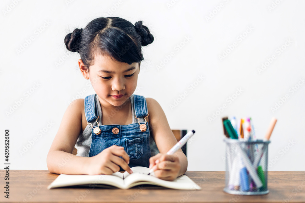 School kid little girl learning and writing in notebook with pencil making homework at home.Education concept School kid little girl learning and writing in notebook with pencil making homework at home.Education concept