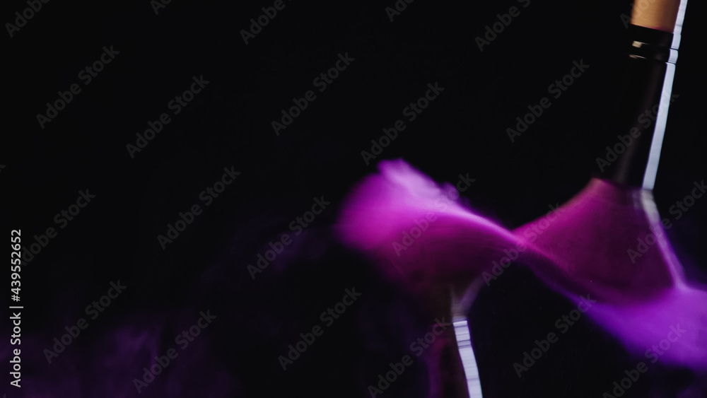 blurred cosmetic brushes with purple powder splashing while hitting on black background