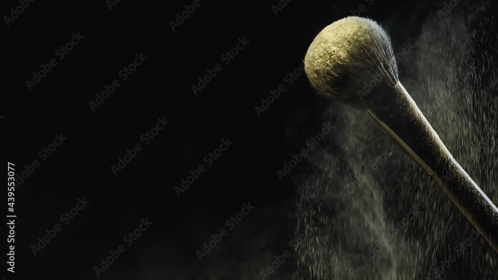 soft cosmetic brush with yellow holi powder on black background soft cosmetic brush with yellow holi powder on black background