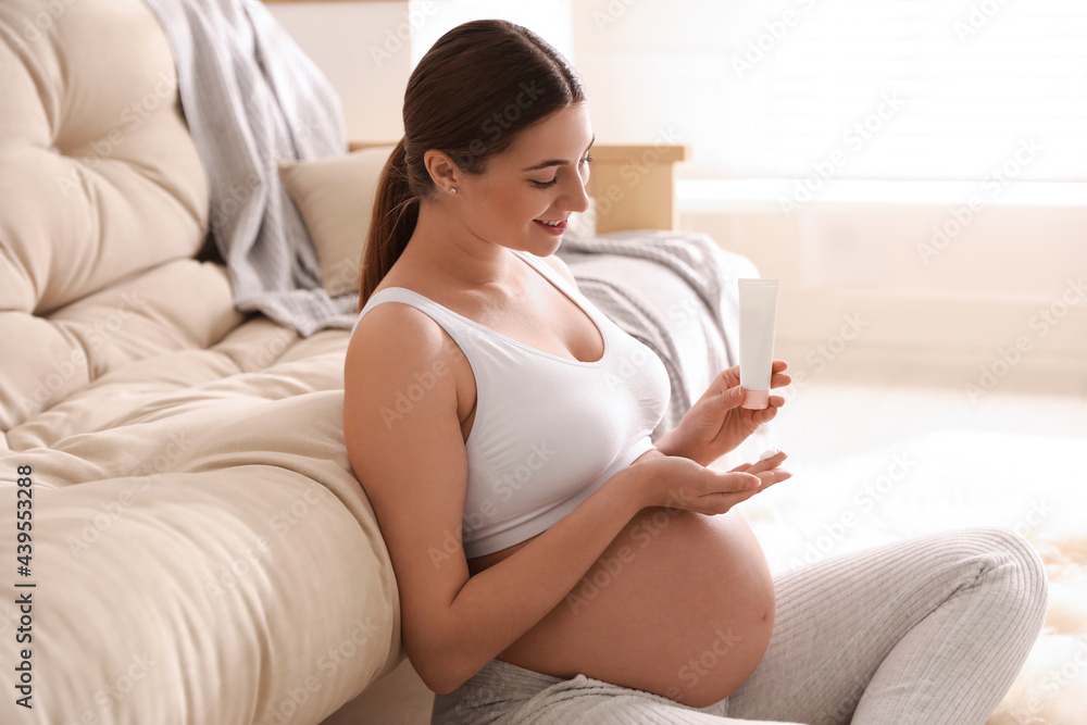 Young pregnant woman with cosmetic product at home Young pregnant woman with cosmetic product at home