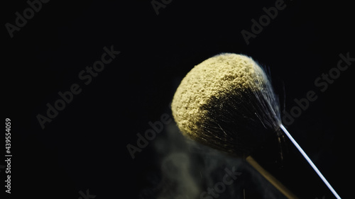 yellow holi powder on soft cosmetic brush isolated on black