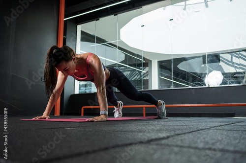 Athletic woman performing push-ups during training at gym