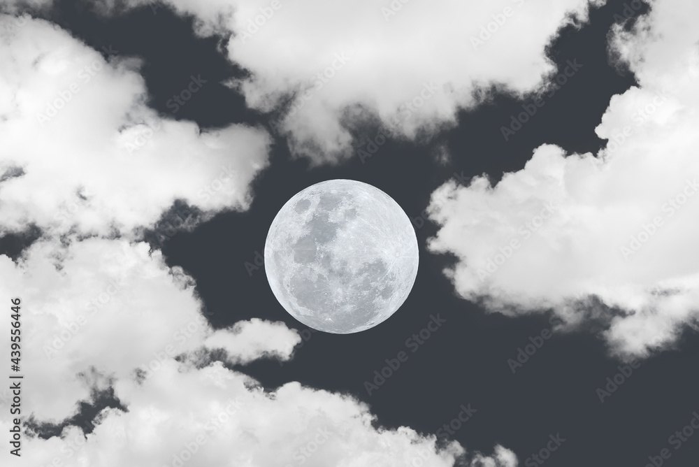 Full moon between clouds on the sky.