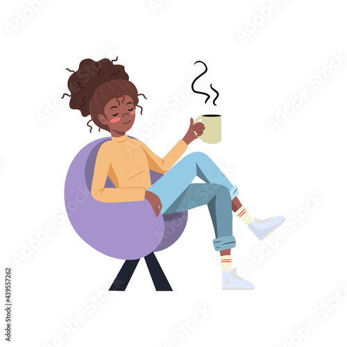 Young woman is having a break, sitting in a modern chair relaxing and drinking coffee