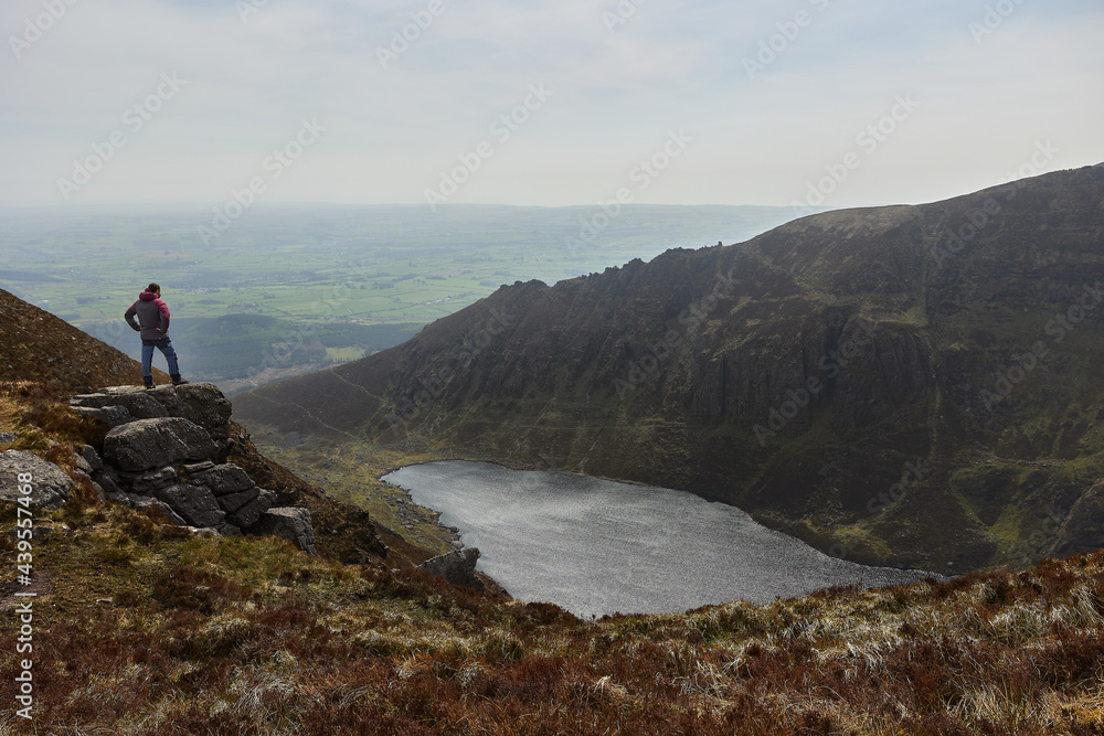 man looking at the landscape of a lake and some immponent mountains. Comeragh Mountains, Waterford, Ireland