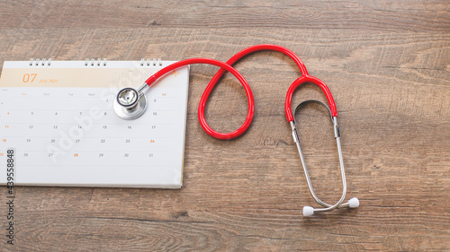 Calendar, stethoscope, on a wood background, health care concept.