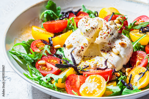 Close-up of burrata cheese salad with arugula and tomatoes. photo