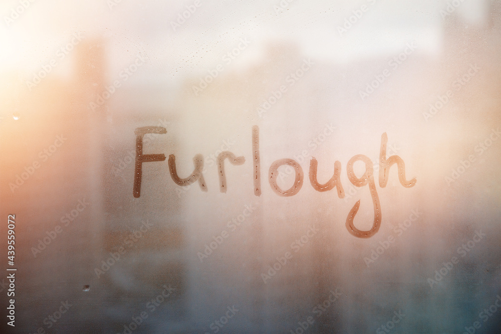 Fototapeta premium Foggy glass on window with written finger word Furlough on muddy sunset glass wet window