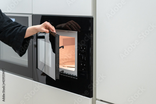 Woman opening new black microwave ovens door