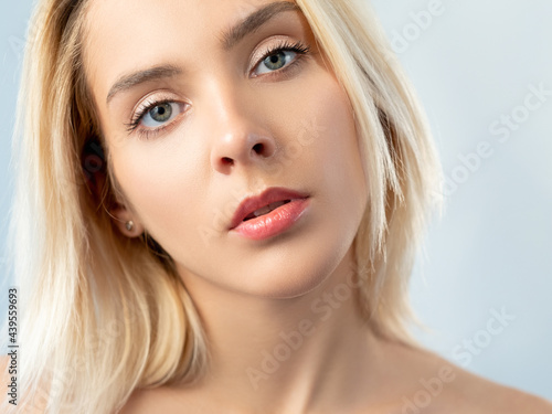 Fresh skin face. Facial skincare cosmetology. Wellness health. Relaxed blonde pretty model woman with nude makeup isolated on light.