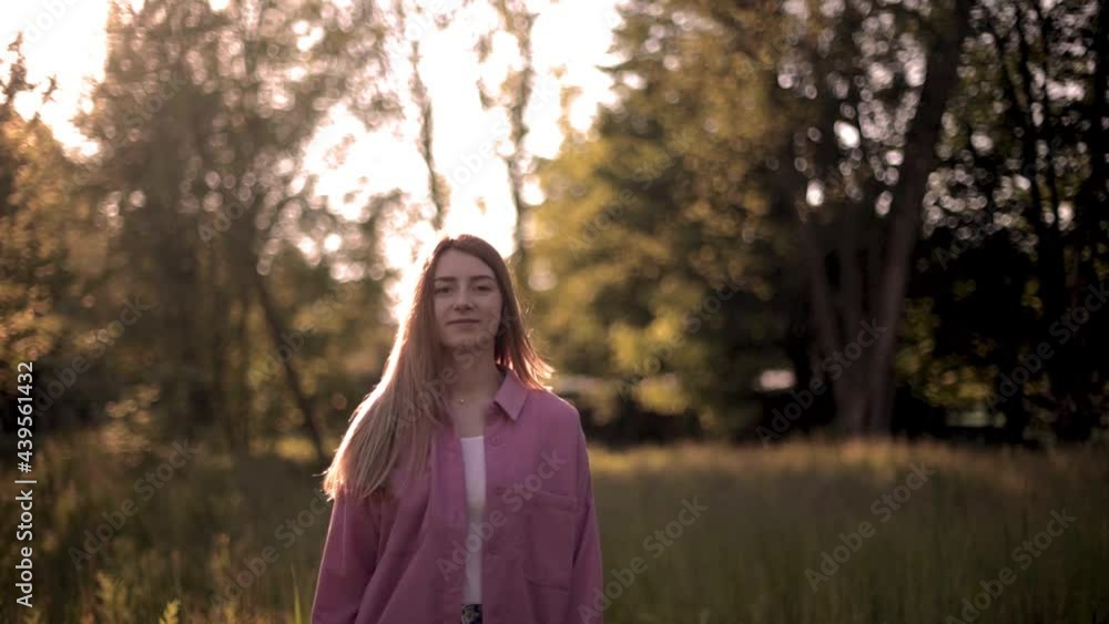 Attractive fashion model walking and spinning in park. Portrait of young beautiful blonde woman in the flowered garden in the spring time. Blossoms fall from trees. Slow motion Attractive fashion model walking and spinning in park. Portrait of young beautiful blonde woman in the flowered garden in the spring time. Blossoms fall from trees. Slow motion