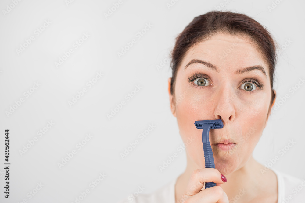 Caucasian funny woman shaves her face with a straight razor on a white background. Copy space. Caucasian funny woman shaves her face with a straight razor on a white background. Copy space.
