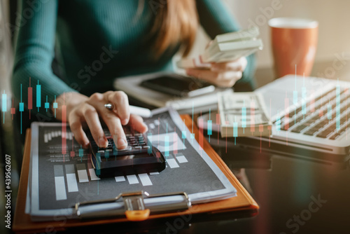 Businesswomen broker Analyzing finance data graphs and reports on screen for investment purposes for trading graph of stock market at home office.