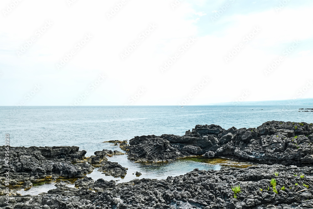 View of the gulf of Giardini Naxos with solidified volcanic lava. Beauty in Sicily as a tourist attraction. Season on mediterranean sea. Ionian sea. View of the gulf of Giardini Naxos with solidified volcanic lava. Beauty in Sicily as a tourist attraction. Season on mediterranean sea. Ionian sea.