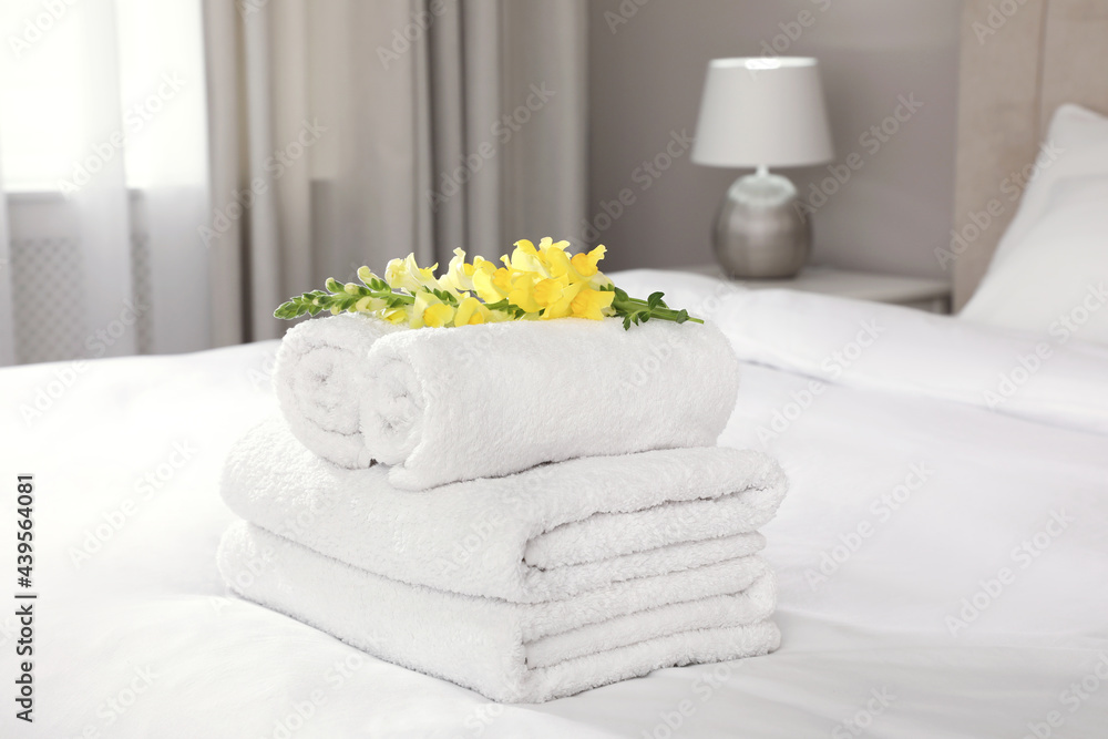 Fresh white towels with flower on bed indoors Fresh white towels with flower on bed indoors