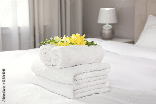 Fototapeta Naklejka Na Ścianę i Meble -  Fresh white towels with flower on bed indoors