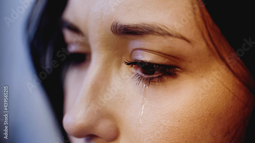 close up view of upset woman crying with tears on face on grey background photo