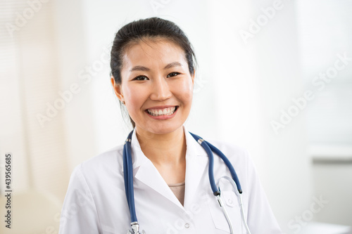Portrait of smiling asian female doctor in a gray background for your text.