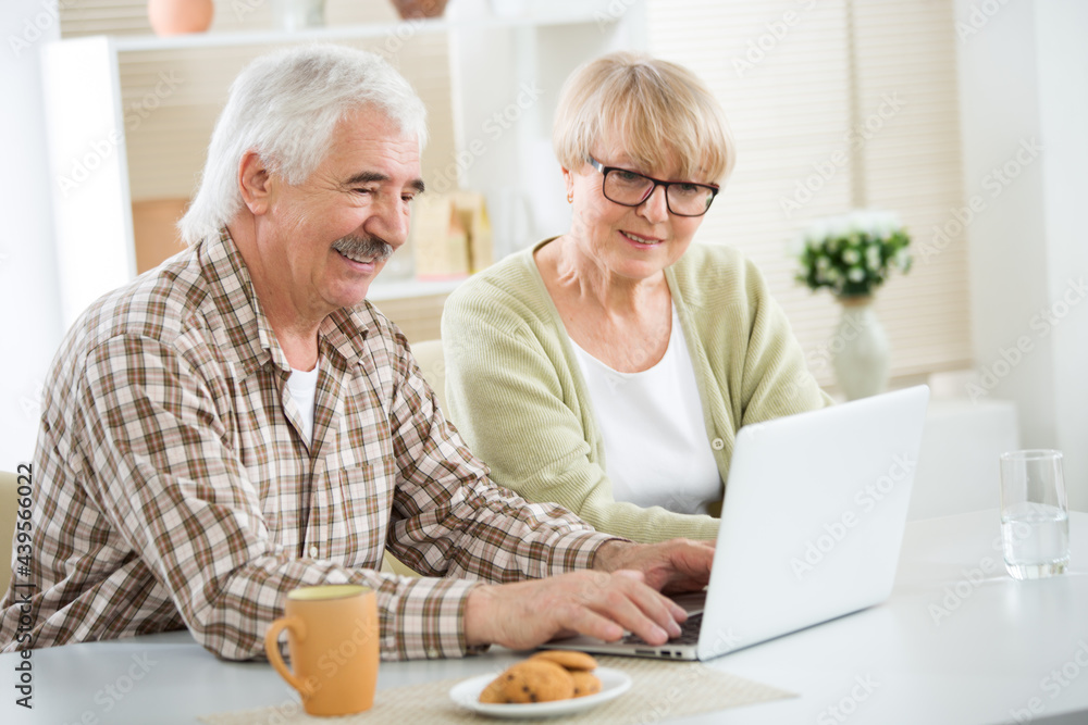 Elderly couple talking using laptop having breakfast together