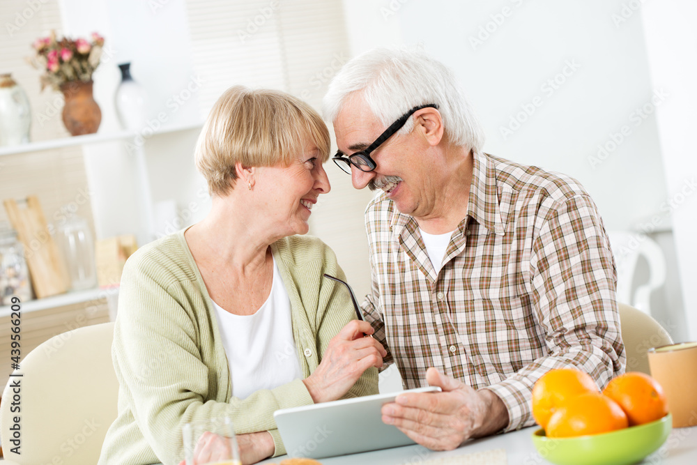 Elderly couple talking using tablet computer having breakfast together Elderly couple talking using tablet computer having breakfast together