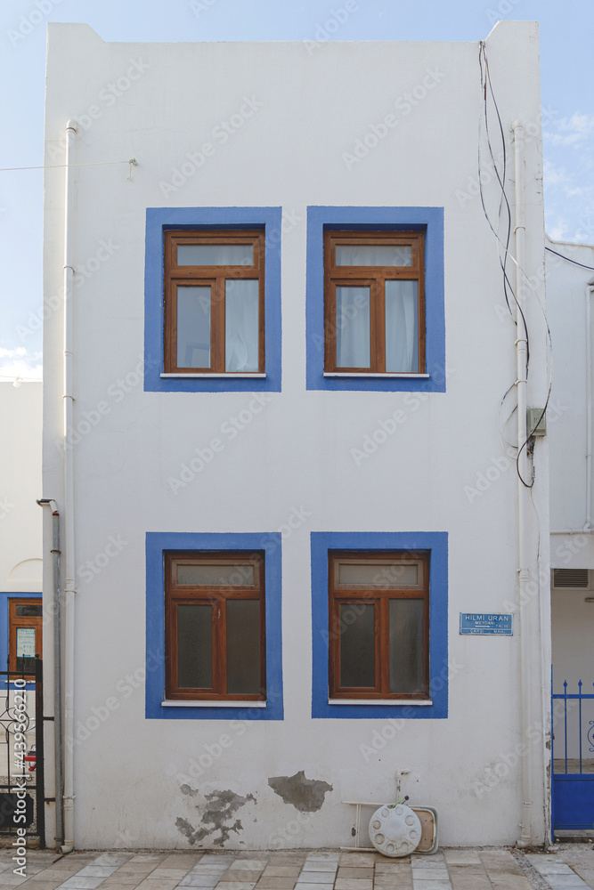 A white building with blue window frames against a blue sky in the Greek style. Travel and architecture concept. High quality photo