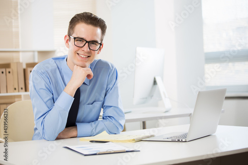 Portrait of young businessman working with laptop at office