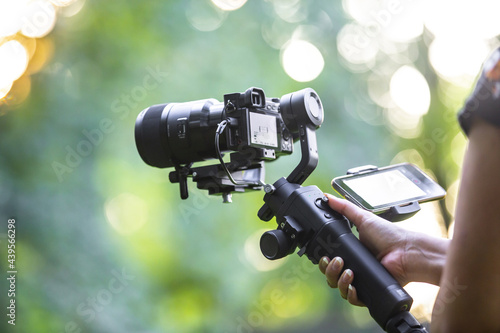 A girl operating camera mounted on a gimbal, focus on the gimbal and camera.