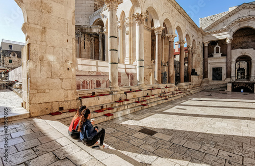 Two women drinking coffee on steps on Peristyle in Diocletian's palace in Split, Croatia. photo