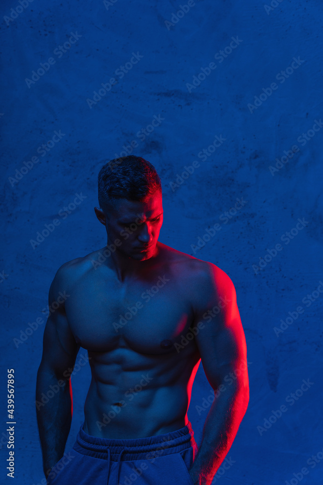 Fototapeta premium Bodybuilder is posing in the colorful neon light
