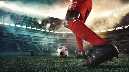 Cropped male soccer, football player in action, motion with ball at the stadium during sport match on light sky background with flashlights.
