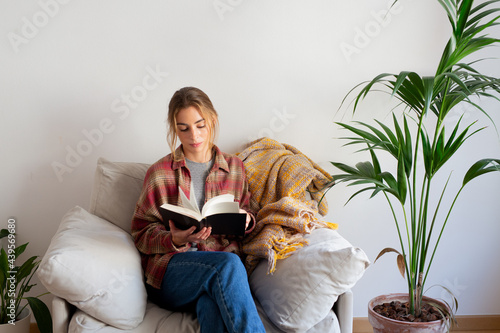 Young woman reading a book in sofa 