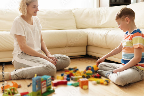 Cute boy and his mother playing together at home