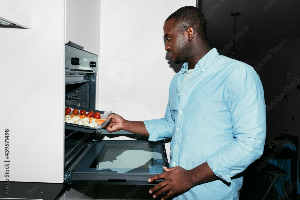 A Man Putting Vegetables in the Oven A Man Putting Vegetables in the Oven