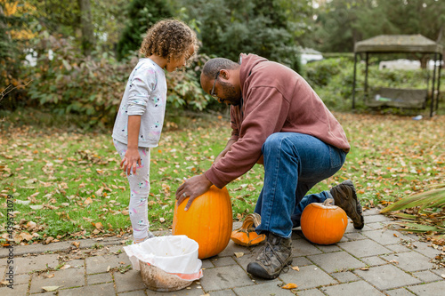  Daughter watches as father carves pumpkin
 photo