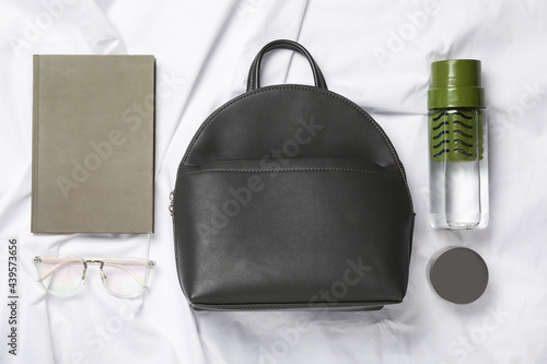Stylish urban backpack and different items on white fabric, flat lay