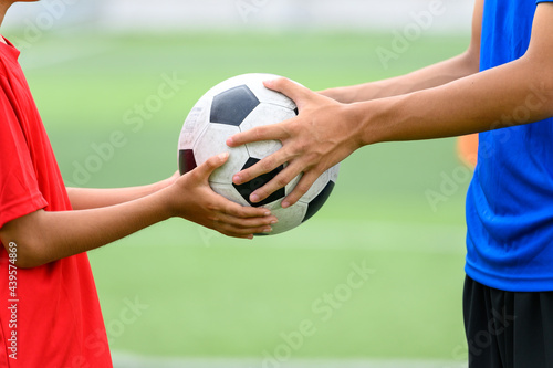 Asian teenager Football Players fair play handed a soccer ball to his brother