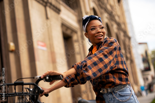 Happy young woman riding bicycle in the city. Beautiful african woman enjoying outdoors