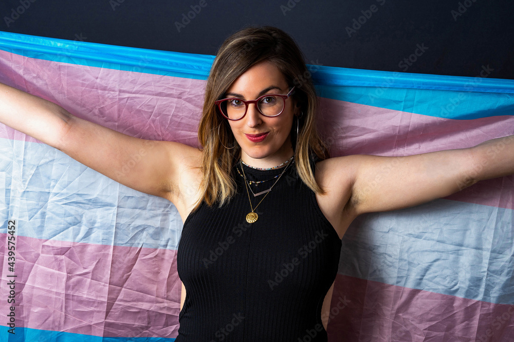 Brunette Haired Transsexual Woman With Glasses And Necklaces Holding A Transgender Lgbt Flag