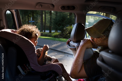 Father turns to talk to daughter in parked minivan photo