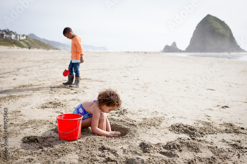 Girl and brother dig in sand at Haystack Rock photo