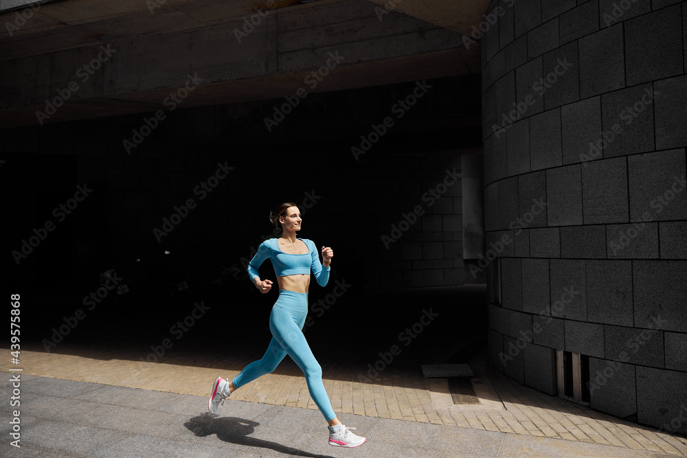 Beautiful fit young woman jogger is running outdoors