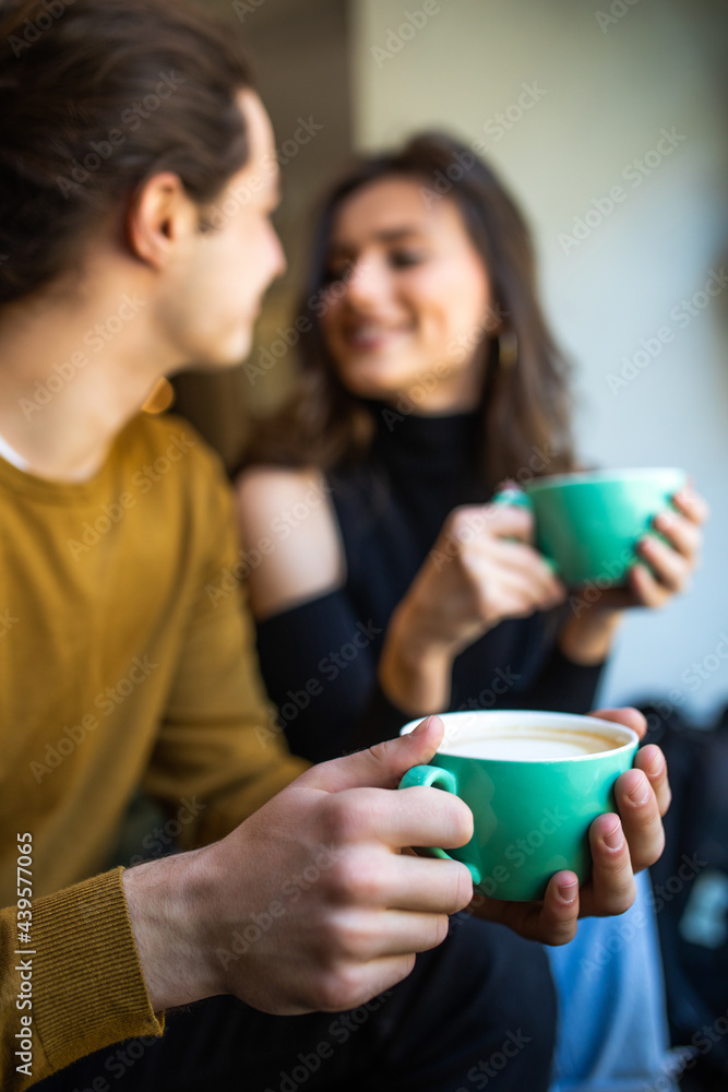 Happy young couple is drinking coffee and smiling while sitting at the cafe Happy young couple is drinking coffee and smiling while sitting at the cafe