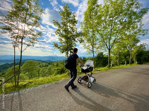 Father walking baby in a stroller on a beautiful day with gorgeous landscape in the background
